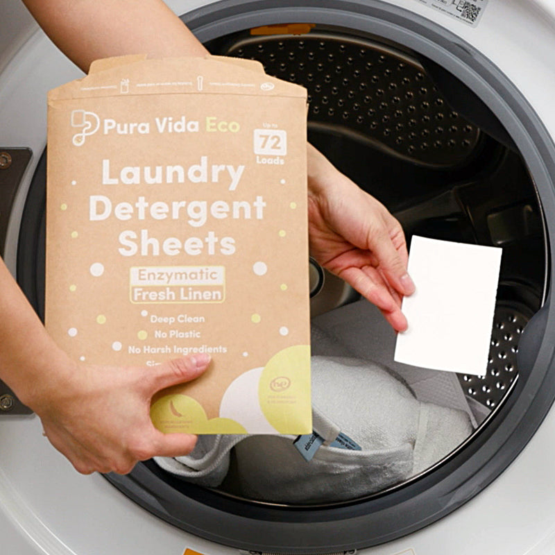 person holding Pura Vida package and single laundry sheet in front of open clothes dryer